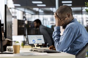 Corporate black CEO experiences job pressure at the office, feeling overwhelmed and stressed by administrative tasks and deadlines. Male expert dealing with low energy and frustration.