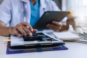 Doctor hold tablet, conduct financial transactions with calculate expenses - income and data documents, put on the desk in the morning.