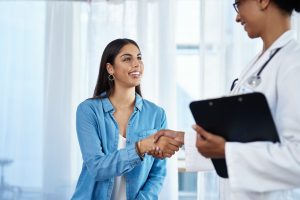 Shot of a young doctor shaking hands with a patient in her consulting room.